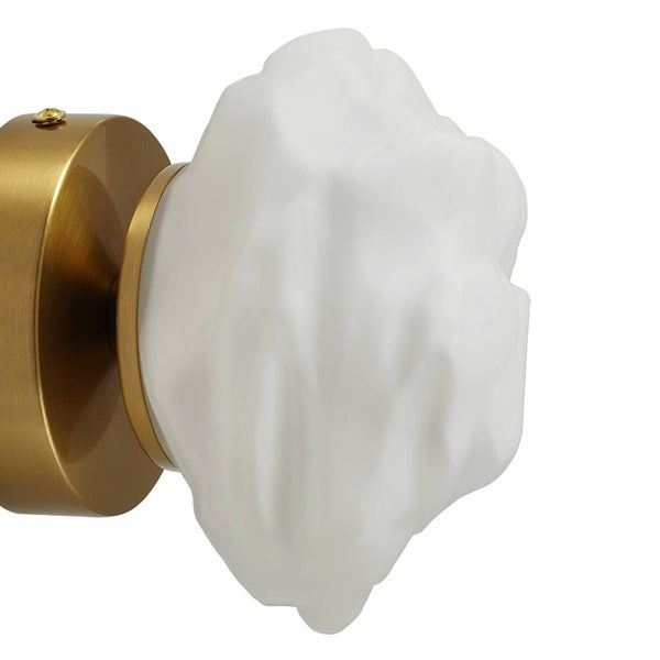 Wandleuchte mit goldfarbenem Metallsockel und strukturiertem, weißem Glasschirm in unregelmäßiger Form.