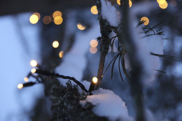 Dekorative Szene mit Papiersternleuchte, Kerzen, einem Stuhl und einer Holztür.