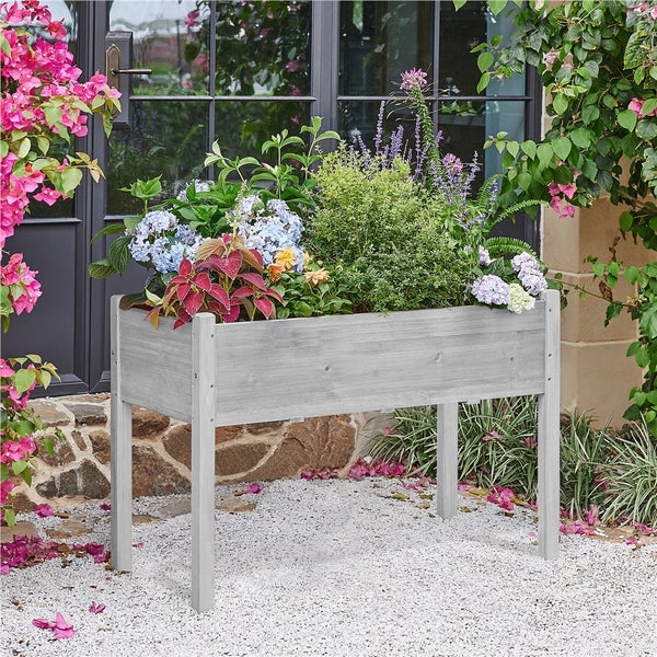 Hochbeet aus Holz mit verschiedenen Pflanzen im Garten.