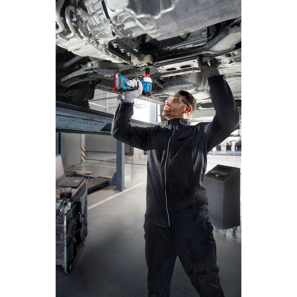 Ein Mann benutzt einen Akku-Schlagschrauber zur Autoreparatur.