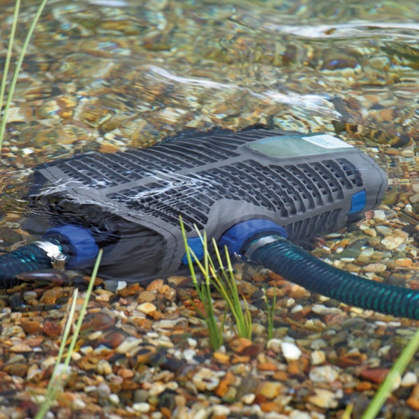 Teichfilterpumpe unter Wasser in einem Gartenteich auf Kies mit zwei angeschlossenen Schläuchen.
