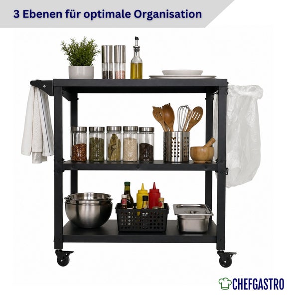 Schwarzer mobiler Küchenwagen mit drei Ebenen, organisiert mit Gewürzen, Utensilien und Schüsseln. Mit Handtuch- und Abfallsackhalter. ChefGastro Logo.