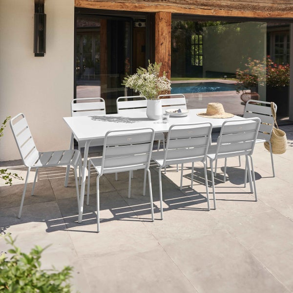 Moderne Garten-Sitzgruppe mit weißem rechteckigem Gartentisch und acht weißen Gartenstühlen aus Metall auf einer Steinterrasse.
