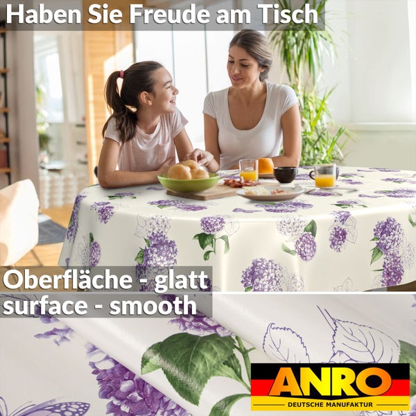Runde Tischdecke mit Hortensien-Muster in hellem Esszimmer. Nahaufnahme zeigt glatte Oberfläche und ANRO Deutsche Manufaktur Logo.