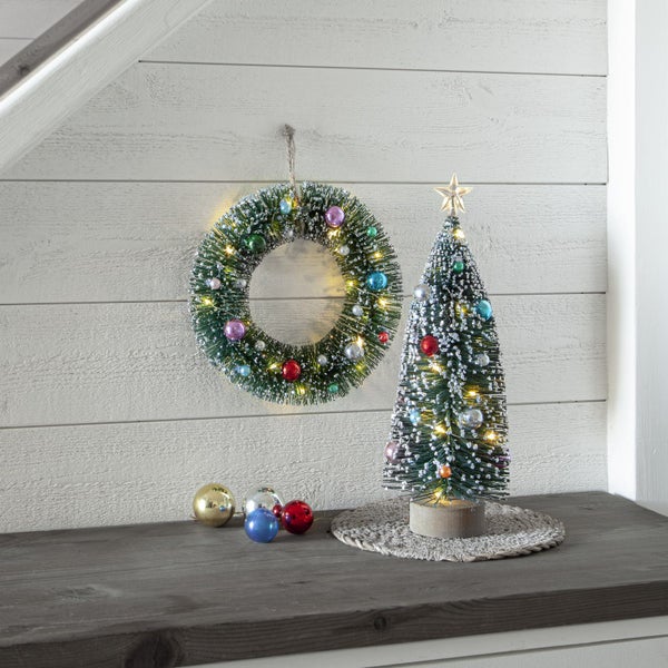 Dekorative Weihnachtsszene mit Kranz, Baum und Kugeln