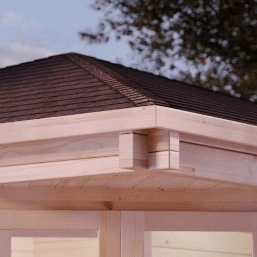 Nahaufnahme der Dachkonstruktion eines Gartenhauses aus hellem Holz mit dunklen Dachschindeln und Eckverbindungen.