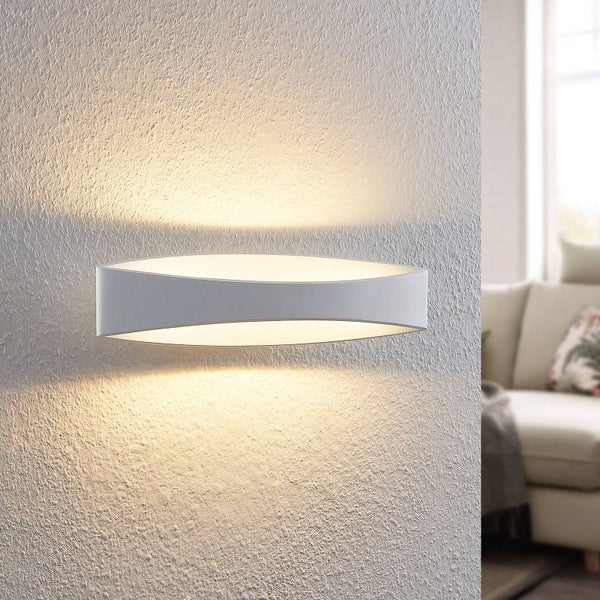 Weiße ovale Wandleuchte mit Lichtaustritt nach oben und unten an einer strukturierten Wand im Wohnzimmer.