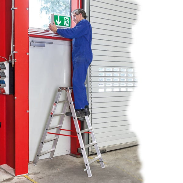 Mann auf Trittleiter montiert Schild in einem Industriebereich
