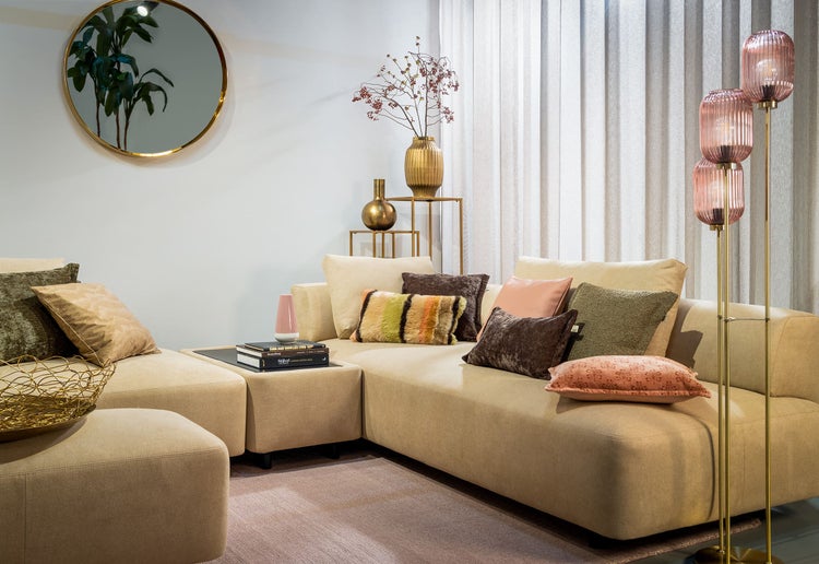 Wohnzimmer mit Ecksofa, Kissen, Stehlampe und dekorativen Accessoires