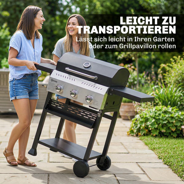 Zwei Frauen transportieren einen mobilen Gasgrill mit drei Brennern auf einer Terrasse im Garten.