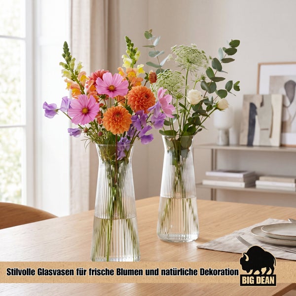 Zwei geriffelte Glasvasen auf einem Holztisch, dekoriert mit einem frischen Blumenstrauß und Eukalyptuszweigen für eine natürliche Wohnraumdekoration.