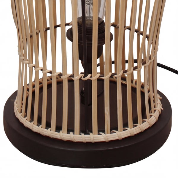 Nahaufnahme einer Tischleuchte mit dunklem rundem Fuß und einem Schirm aus hellen Bambusstäben.