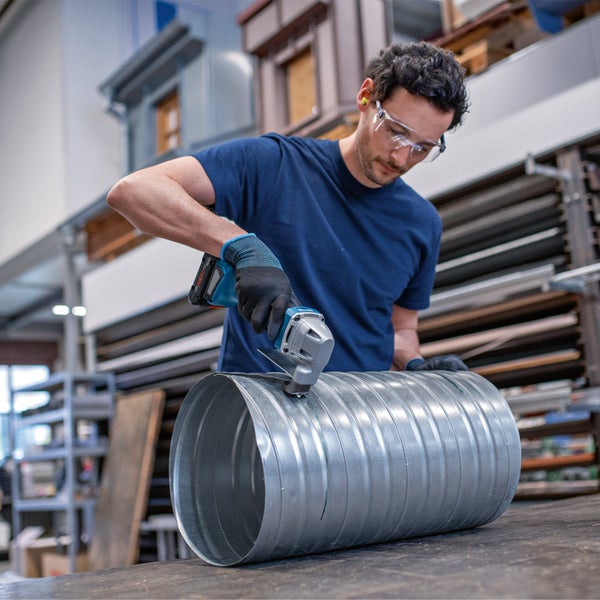 Ein Mann schneidet mit einer Blechschere ein verzinktes Rohr.