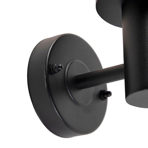 Detailansicht der schwarzen Metallwandhalterung einer Wandleuchte.