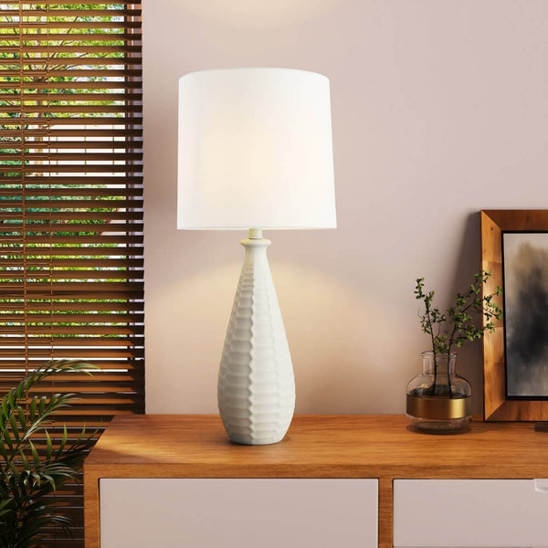 Tischlampe mit weißem Lampenschirm auf einem Nachttisch