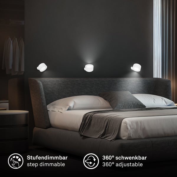 Modernes Schlafzimmer mit drei weißen runden LED-Wandleuchten über einem Polsterbett. Stufendimmbar und 360 Grad schwenkbar.