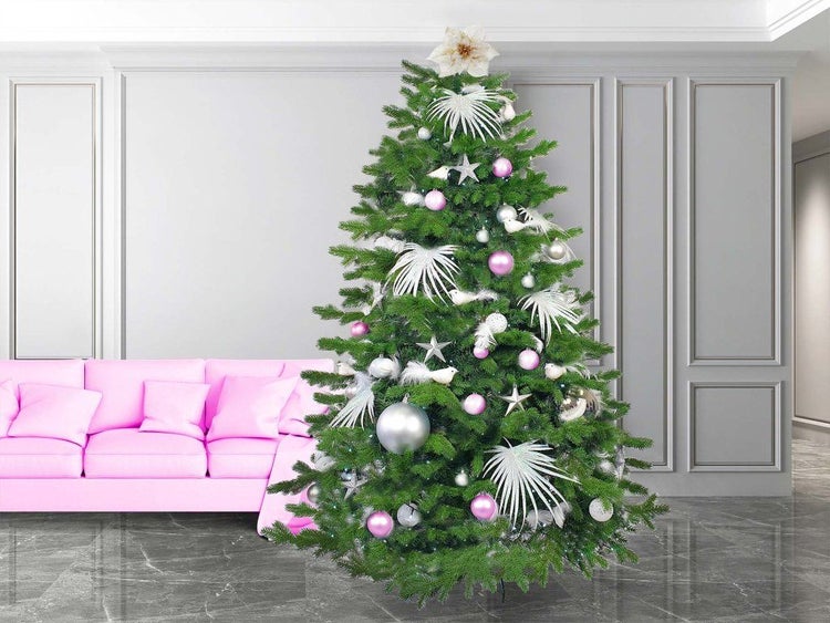 Ein geschmückter künstlicher Weihnachtsbaum mit Weihnachtskugeln und Sternen in einem Wohnzimmer mit Sofa.