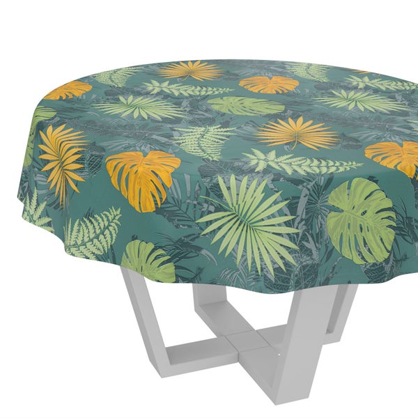 Rundes Tischtuch mit tropischem Blattmuster aus Monstera- und Farnblättern auf einem Tisch.