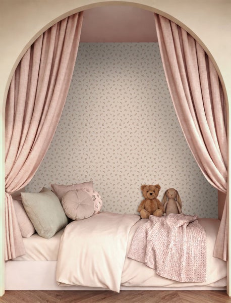 Kinderzimmer in einer bogenförmigen Nische mit gemusterter Tapete, gerafften Vorhängen und Bett mit Kissen und Stofftieren.