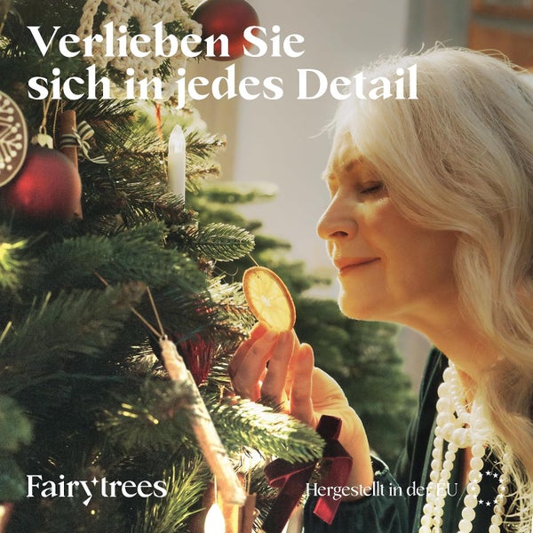 Eine Frau betrachtet eine künstliche Fairy Trees Weihnachtsbaum Dekoration mit getrockneten Orangenscheiben und Schmuck.