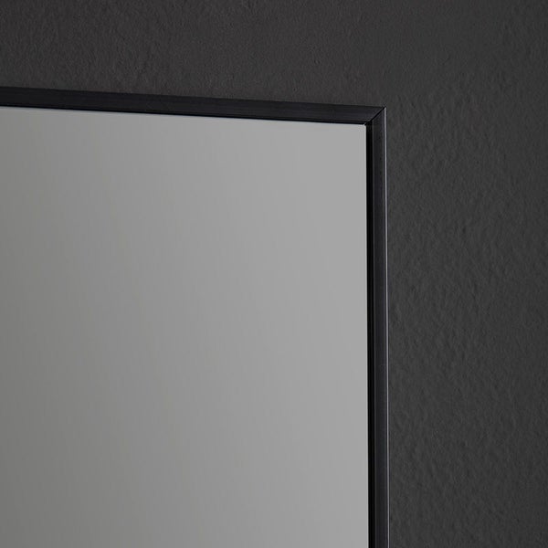 Detailansicht der Ecke eines Wandspiegels mit einem schmalen schwarzen Rahmen.