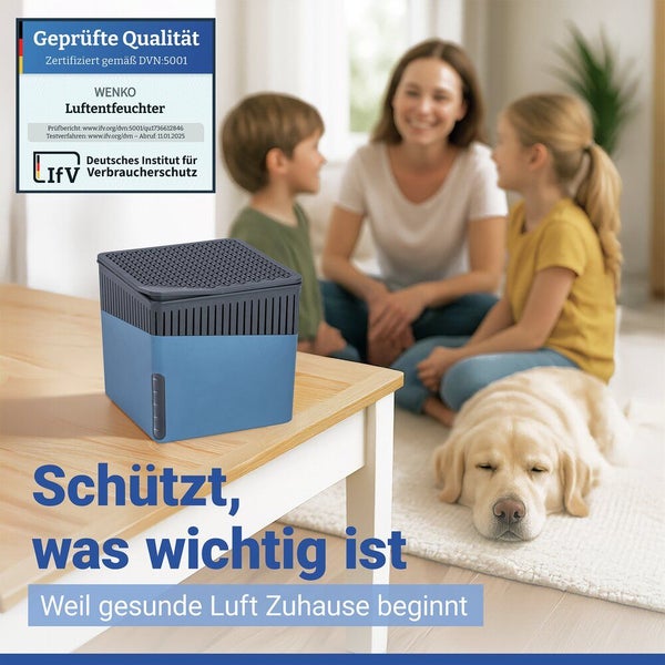 Wenko Luftentfeuchter auf einem Tisch mit Familie und Hund im Hintergrund. Deutsches Institut für Verbraucherschutz Logo.