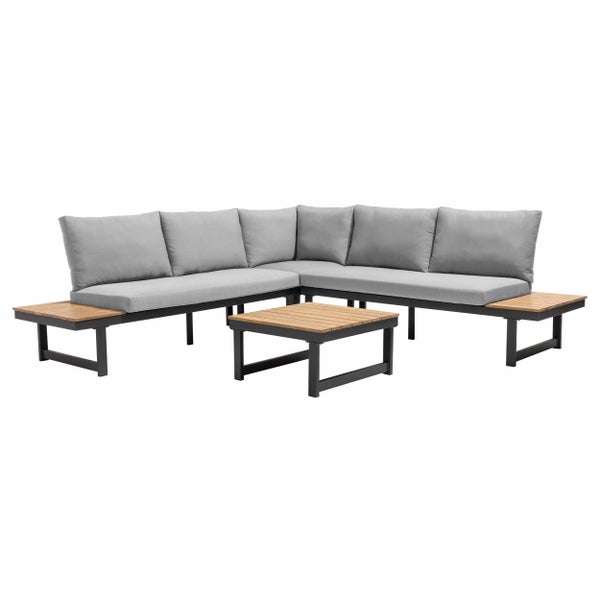 Moderne Gartenlounge mit grauem Ecksofa und Holztisch auf einer Steinterrasse vor einem Haus mit Reetdach.