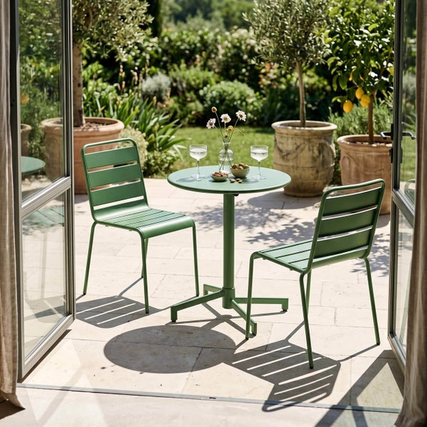 Modernes Bistro-Set aus Metall mit zwei Stühlen und einem runden Tisch in Grün auf einer hellen Terrasse mit Gartenblick.