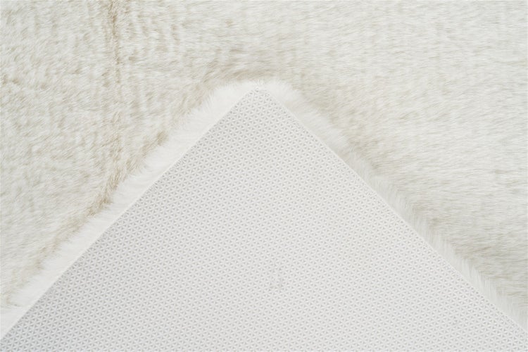 Nahaufnahme eines Kunstfellteppichs mit weicher Oberfläche und rutschhemmender Rückseite.