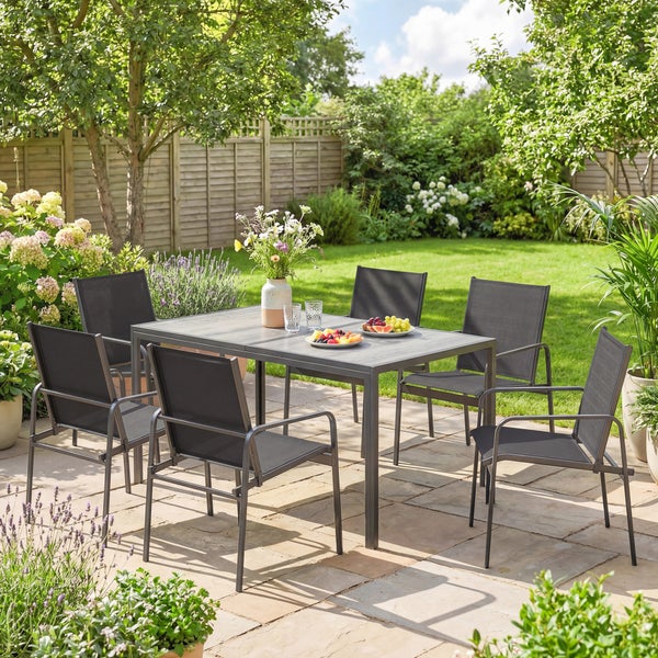 Gartenmöbel-Set mit einem rechteckigen Metalltisch und sechs grauen Textilstühlen auf einer sonnigen Steinterrasse im grünen Garten.