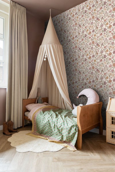 Kinderzimmer mit floral gemusterter Tapete, Holzbett mit Baldachin, Vorhängen und hellem Fischgrätenparkett.