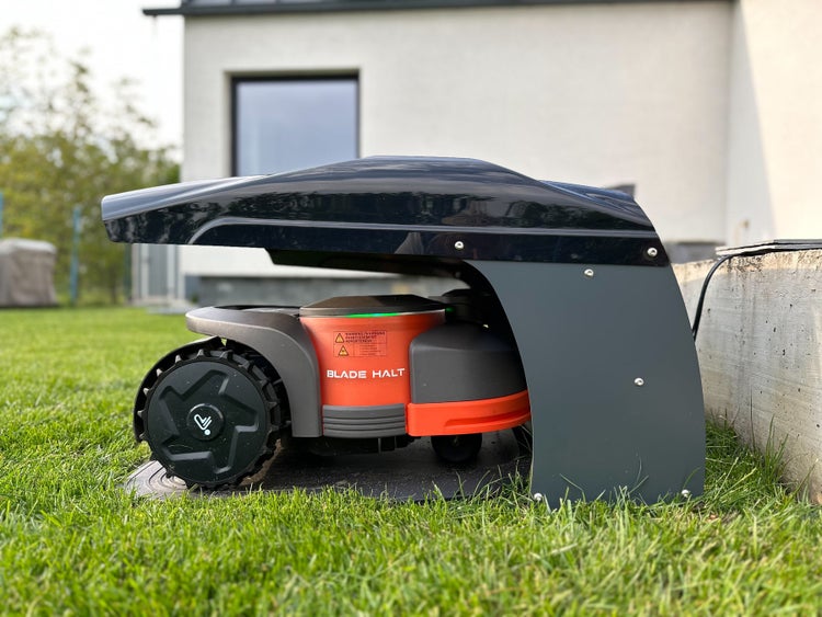 Rasenmähroboter auf einer Rasenfläche vor einem Haus