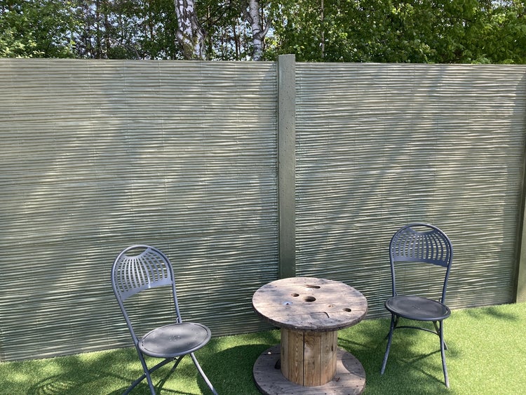 Garten mit Sichtschutzzaun, zwei Stühlen und einem Tisch aus einer Kabeltrommel