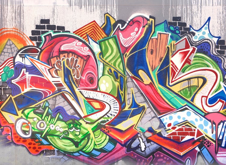 Fototapete mit farbenfroher Graffiti-Kunst, abstrakten Formen, Comic-Elementen und Backsteinoptik.