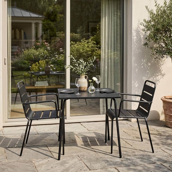 Modernes Gartenmöbel-Set bestehend aus einem quadratischen schwarzen Metalltisch und zwei passenden Armlehnstühlen auf einer Steinterrasse.