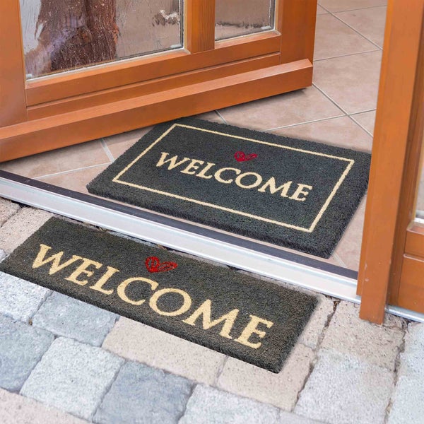 Fußmatte mit Willkommensgruß vor einer Haustür