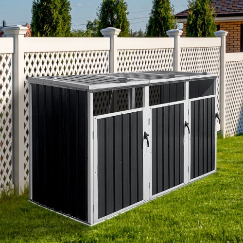 Mülltonnenbox aus Metall für drei Mülltonnen im Garten auf einer Rasenfläche vor einem Zaun.