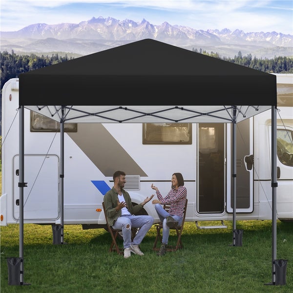 Szene mit einem schwarzen Faltzelt vor einem Wohnmobil, unter dem zwei Personen sitzen