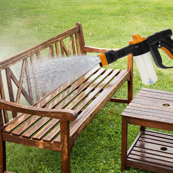 Eine Holzbank wird mit einem Reinigungsgerät im Garten gereinigt.