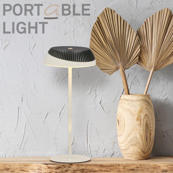 Moderne tragbare Tischleuchte mit schlankem Standfuß und geripptem Schirm, neben einer Holzvase mit getrockneten Palmblättern.