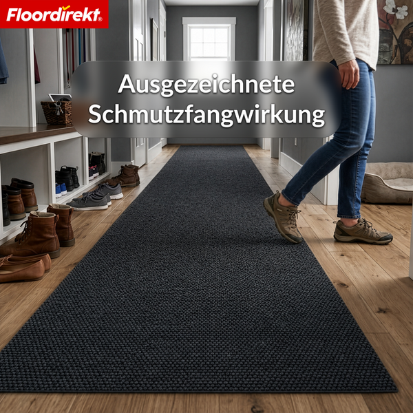Dunkelgrauer Schmutzfangläufer in einem hellen Flur mit weißem Schuhregal und Holzfußboden. Floordirekt Logo.