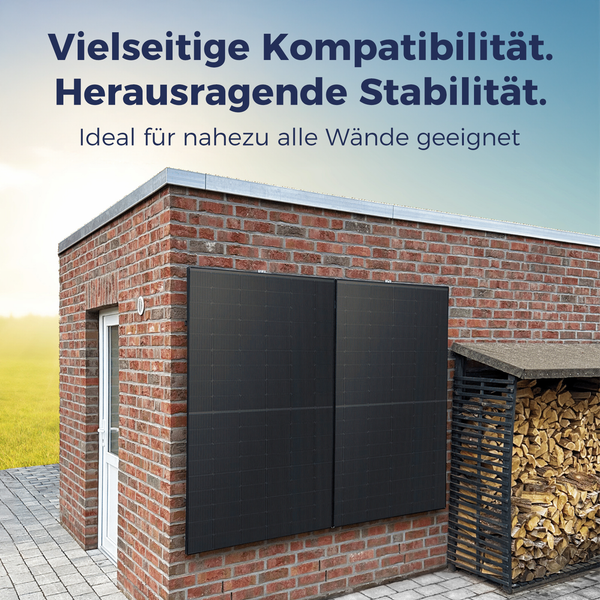 Zwei Photovoltaik-Module für die Wandmontage an einer Ziegelmauer eines Nebengebäudes neben einem Brennholzlager.