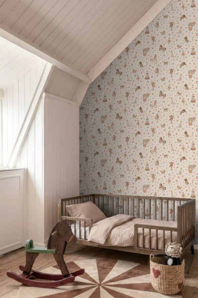Kinderzimmer mit Zirkus Tapete, Kinderbett aus Holz, Schaukelpferd und dekorativem Korb auf einem runden Teppich.