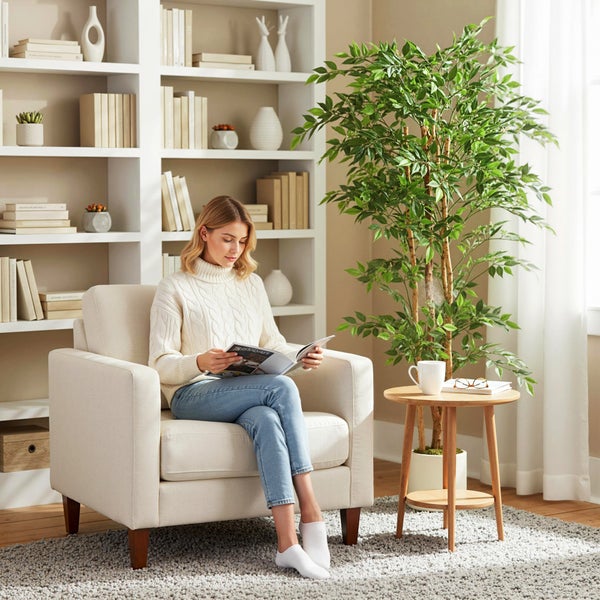 Wohnzimmer mit Sessel, Beistelltisch und Bücherregal, in dem eine Frau ein Buch liest.