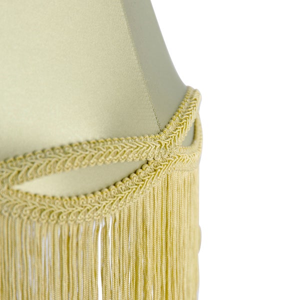 Detailansicht eines Lampenschirms mit dekorativer Borte und Fransen aus Textil.