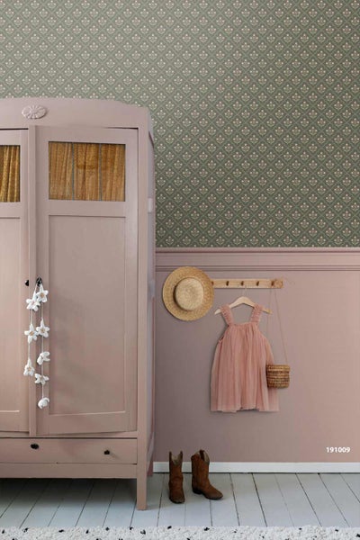 Romantisches Kinderzimmer mit floral gemusterter Vliestapete, Wand mit Zierleiste, Holzschrank sowie einer Hakenleiste mit Kleidung und Hut.