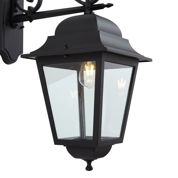 Schwarze Außenwandleuchte in klassischer Laternenform mit Klarglas und leuchtendem LED-Filament-Leuchtmittel.