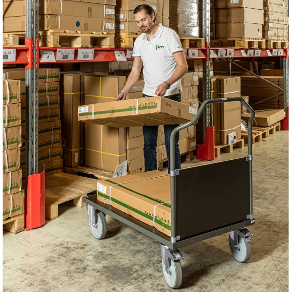 Mitarbeiter räumt Waren in einem Lager auf einen Transportwagen