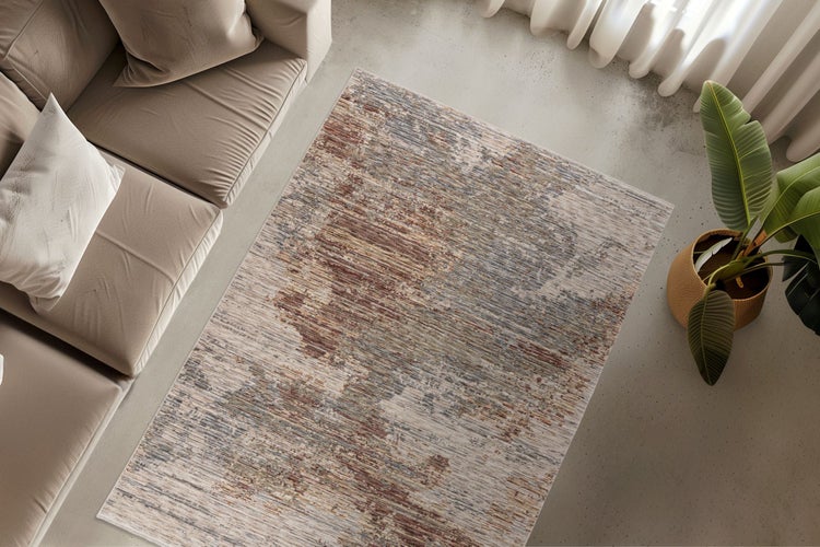 Ein rechteckiger Teppich mit abstraktem Muster liegt in einem modern eingerichteten Wohnzimmer vor einem Sofa auf einem Betonboden.