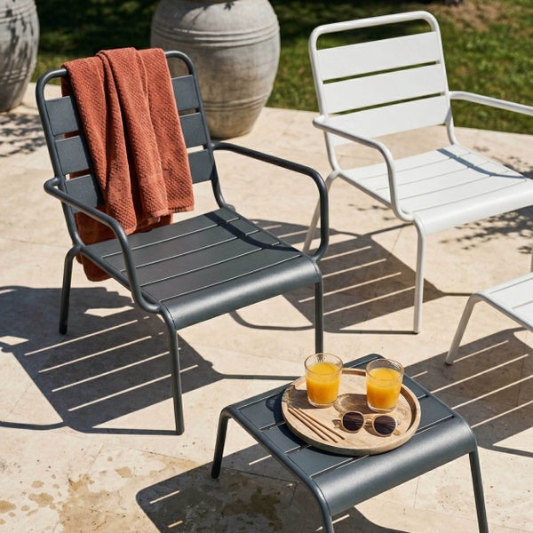 Zwei moderne Gartenstühle aus Metall in Anthrazit und Weiß auf einer Terrasse mit passendem Beistelltisch und Holztablett.